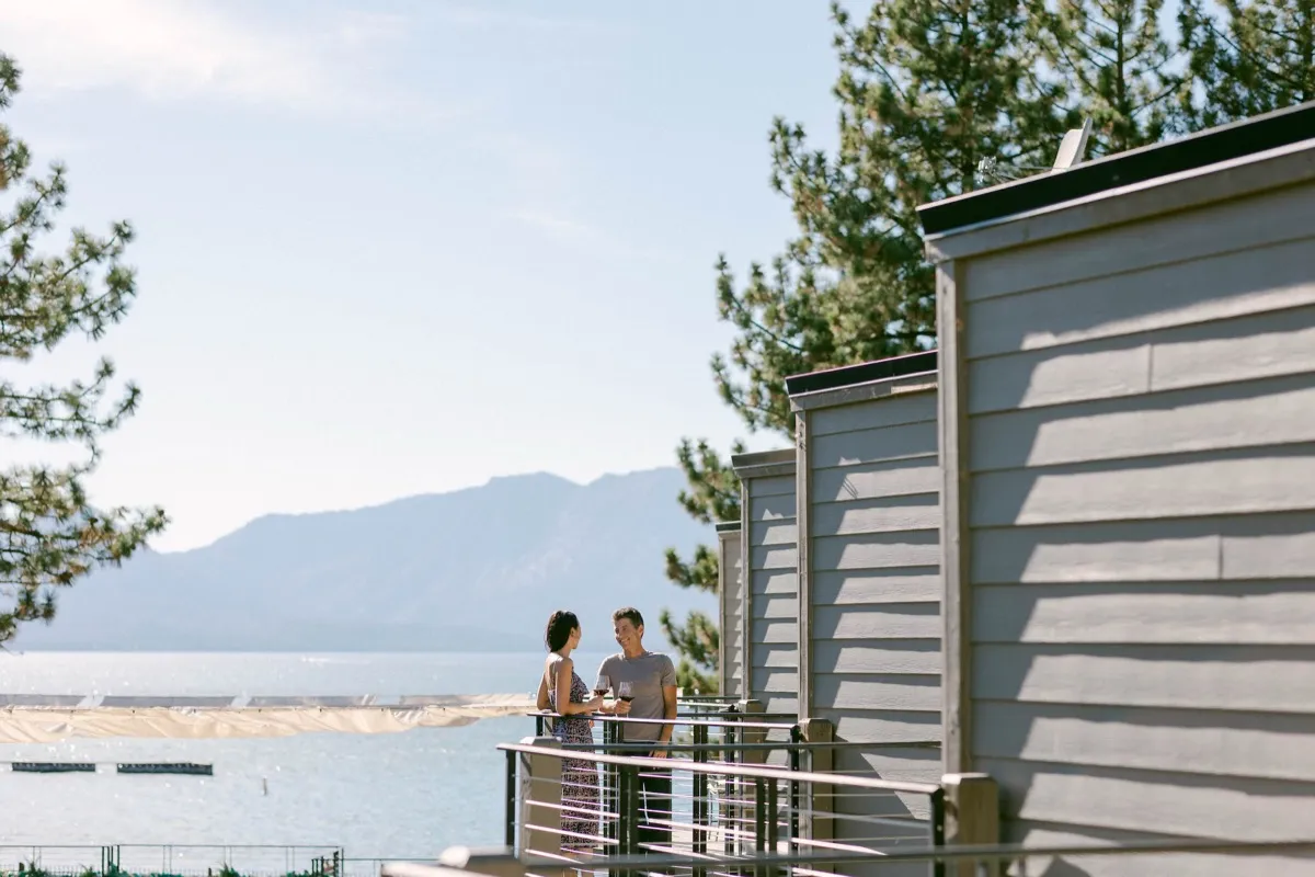 Two guests with wine on a balcony overlooking Lake Tahoe